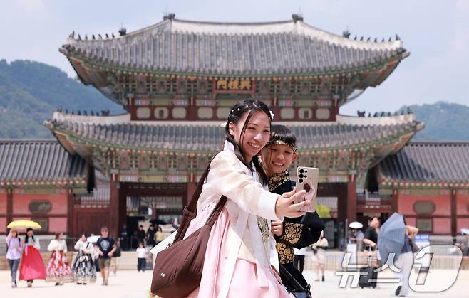 14일 서울 종로구 경복궁에서 한복을 입은 외국인 모자가 셀카를 찍고 있다. 이날 한국문화관광연구원의 '국제관광시장 전망'에 따르면 원화 가치가 하락하면서 한국 여행 비용 부담이 줄자 외국인 관광객 급증해 올해 방한 관광객은 약 2200만명으로 전망된다. 이는 전년 대비 16.2% 증가한 수준이다. 2026.6.14 ⓒ 뉴스1 이호윤 기자