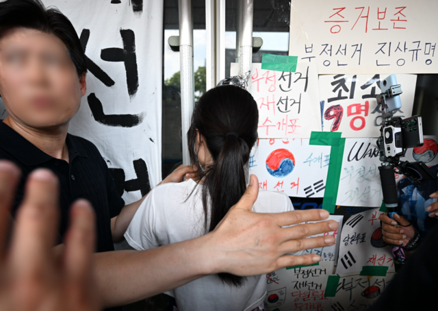6·3 지방선거 투표용지 부족 사태로 시작한 서울 송파구 올림픽공원 핸드볼경기장 일대 ‘개표소 봉쇄 시위’가 이어지는 가운데 16일 한 시위 참가자가 대한체육회 등 입주 단체 관계자들의 진입을 막아서고 있다. 공동취재