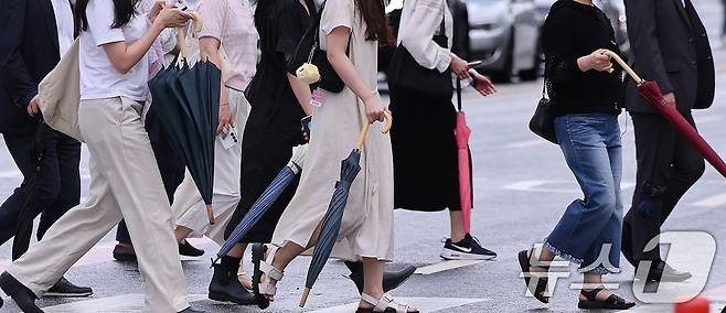 7일 서울 광화문네거리에서 출근하는 시민들이 비가 내렸다 그치기를 반복하는 날씨 속에 우산을 손에 든 채 발걸음을 옮기고 있다. 장마철이지만 정체전선이 뚜렷하게 형성되지 않으면서 내륙 곳곳에서는 국지적으로 비가 오락가락하는 날씨가 이어지고 있다. 2026.7.7 ⓒ 뉴스1 박지혜 기자