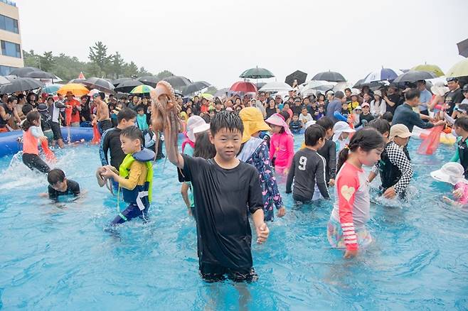 지난해 아야진해변에서 열린 피문어 맨손잡기 축제에서 한 어린이가 직접 잡은 문어를 들어 올리며 즐거워하고 있다. /사진 제공=고성군