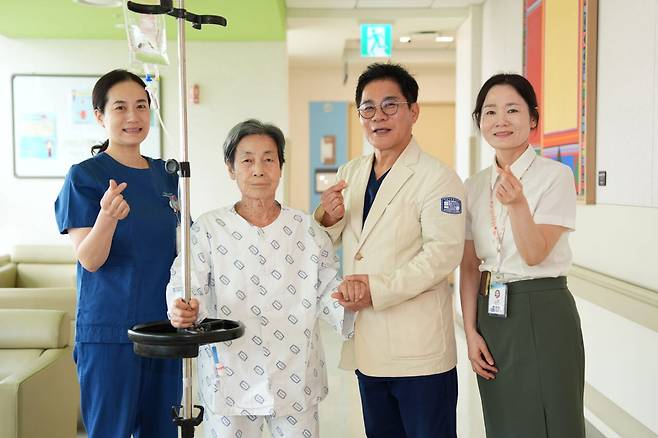 서울성모병원 장기육 교수(환자 옆 오른쪽)와 의료진이 6년전 시술 받은 타비판막의 퇴행성 변화로 중증 대동맥판막으로 진행된 89세 환자를 차세대 TAVI 재시술로 치료하고 건강을 기원하며 기념사진을 촬영했다.