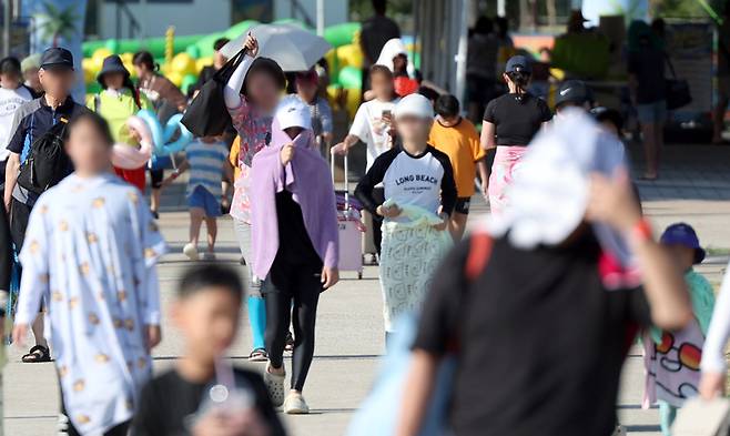 경남 양산지역 낮 최고기온이 40.3도까지 치솟은 지난 29일 오후 양산시 물금읍 운영이 종료된 황산공원 물놀이장을 나서는 피서객들이 모자와 양산으로 뜨거운 햇빛을 가리고 있다. / 사진=연합뉴스