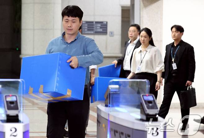 6·3 지방선거 투표용지 부족 사태를 수사 중인 검·경 합동수사본부 관계자들이 23일 오후 경기 과천시 중앙선거관리위원회에 대한 압수수색을 마친뒤 압수상자를 들고 나서고 있다. 이날 검·경 합동수사본부는 선거관리위원회 관계자들의 투표율 통계 조작 정황을 포착해 중앙선관위와 경기도선관위 등에 대한 압수수색에 나섰다.(공동취재) 2026.7.23 ⓒ 뉴스1 이광호 기자