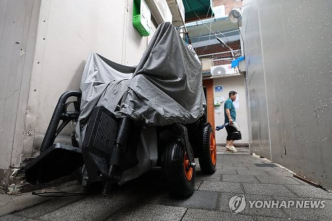 전동휠체어 (서울=연합뉴스) 서대연 기자 = 장맛비가 내린 6일 서울 종로구 돈의동 쪽방촌에 비닐로 덮인 전동휠체어가 세워져 있다. 2026.7.6 dwise@yna.co.kr