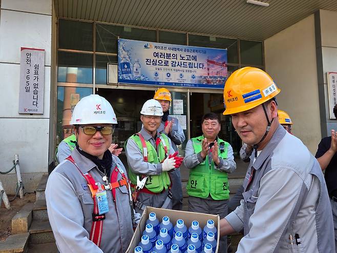 지난 6일 케이조선 성현철 조선소장(왼쪽)과 사내협력사협의회 이용남 대표(오른쪽)가 현장 근로자들에게 이온음료를 전달하고 있다.(사진=케이조선 제공)