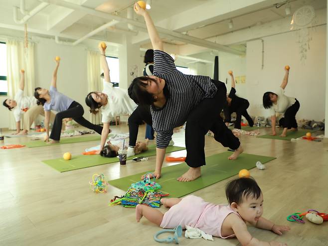 지난 11일 '유아 동반 프로그램'을 운영하는 서울 송파구의 한 요가원. 운동을 하는 엄마 옆에한 아기가 엎드려 놀고 있다./이성현 인턴기자