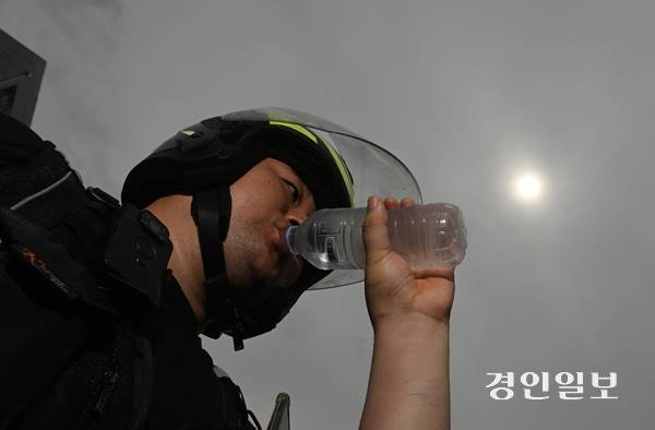 체감 온도가 33℃까지 오른 14일 오후 인천시 남동구 간석동의 한 길가에서 배달 노동자 김진욱씨가 물을 마시며 더위를 식히고 있다. 2026.8.14 /조재현기자 jhc@kyeongin.com