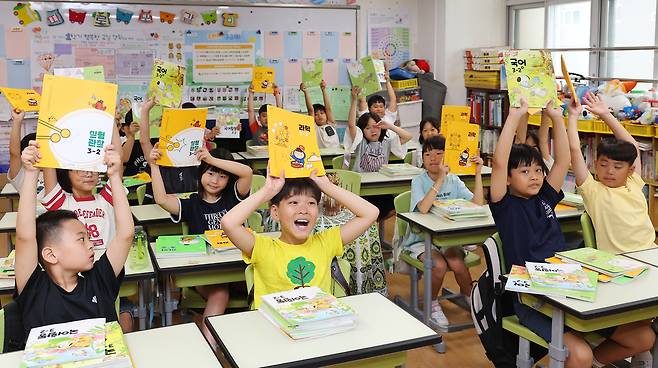 이달 11일 여름방학을 마치고 개학한 인천 부평구 동수초등학교 3학년 1반 교실에서 학생들이 새로 받은 2학기 교과서를 들어 보이고 있다. 연합뉴스