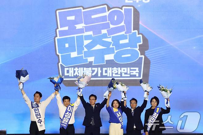 더불어민주당 김민석 신임 당대표와 최고위원들이 17일 오후 대전 유성구 DCC대전컨벤션센터에서 열린 '더불어민주당 제3차 정기전국당원대회'에서 손을 들어 인사하고 있다. 왼쪽부터 한민수, 이성윤, 김 대표, 서미화, 박선원, 최민희. 2026.8.17 ⓒ 뉴스1 황기선 기자
