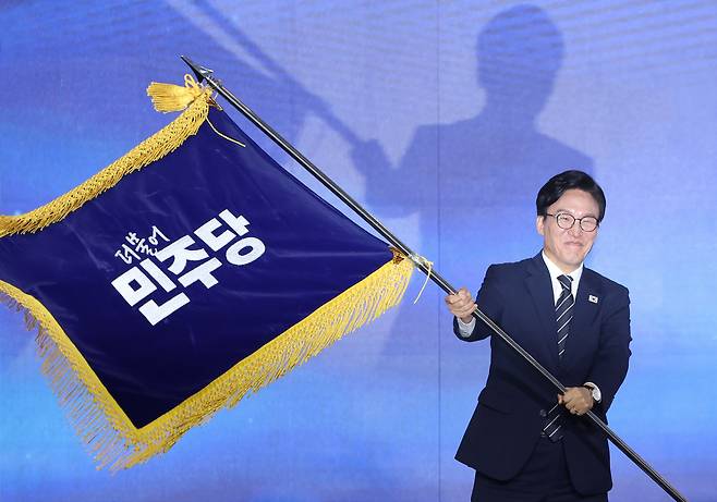 더불어민주당 당 대표에 출마한 김민석 전 총리가 17일 대전 컨벤션센터에서 열린 제3회 더불어민주당 정기 전국당원대회에서 당 대표 당선을 확정한 뒤 당기를 흔들고 있다. 연합뉴스