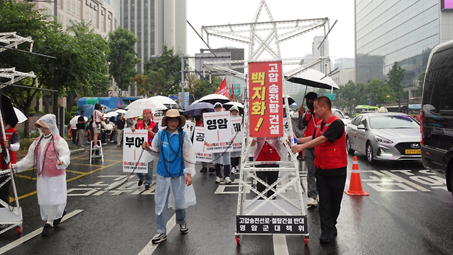 ▲'전국행동'이 20일 서울 종로구 광화문 일대에서 개최한 '해남에서 서울까지, 대통령은 응답하라! 서울 집중행동'에서 참가자들이 송전탑 모형과 송전선에 몸을 묶은 채 걸어가는 퍼포먼스를 펼치고 있다. 이는 지역의 삶이 송전망에 얽매여 있는 현실을 상징적으로 보여준다. 사진=이현진 기자