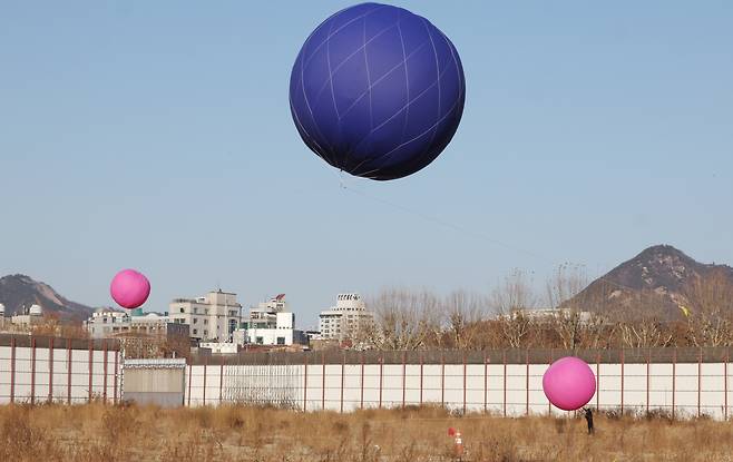 Large balloons float over the Sewoon District 4 site in central Seoul on Dec. 25, 2025, part of a simulation of how buildings planned for the site would affect the view from Jongmyo Shrine. YONHAP