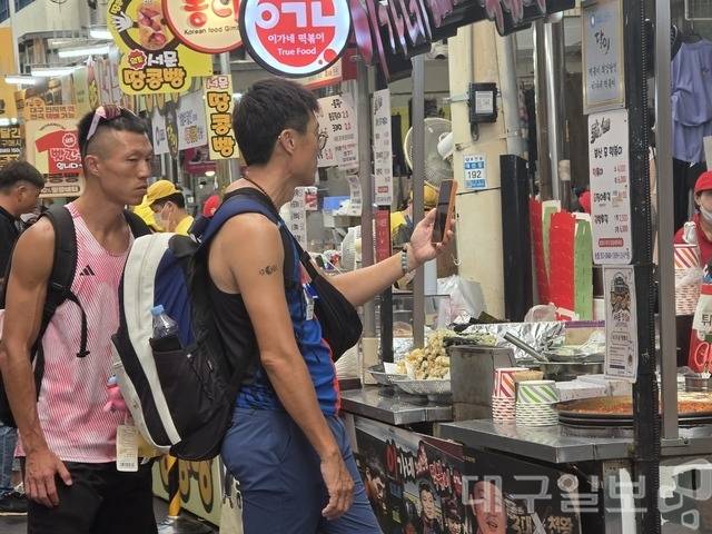 2026 대구세계마스터즈육상경기대회에 출전한 대만 선수들이 24일 오후 대구 서문시장의 한 분식 점포 앞에서 떡볶이와 튀김 등 K-길거리 음식을 먹기위해 기다리고 있다. 김용국 기자