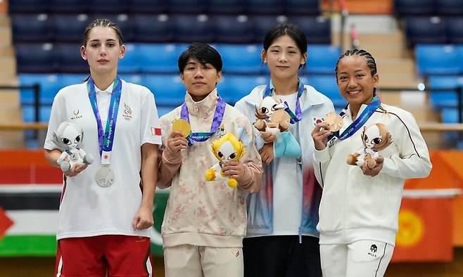 22일 일본 나고야에서 열린 2026 아이치·나고야 아시안게임 종합격투기(MMA) 여자 모던 부문 54㎏ 시상식에서 메달리스트들이 시상대에 서 있다. 왼쪽부터 은메달을 딴 바레인의 디아나 포고시안, 금메달을 딴 타이의 칸주타 파타라분손, 동메달을 딴 한국의 이보미와 인도네시아의 발렌시아 파히라 호트마울리. 나고야/AP 연합뉴스