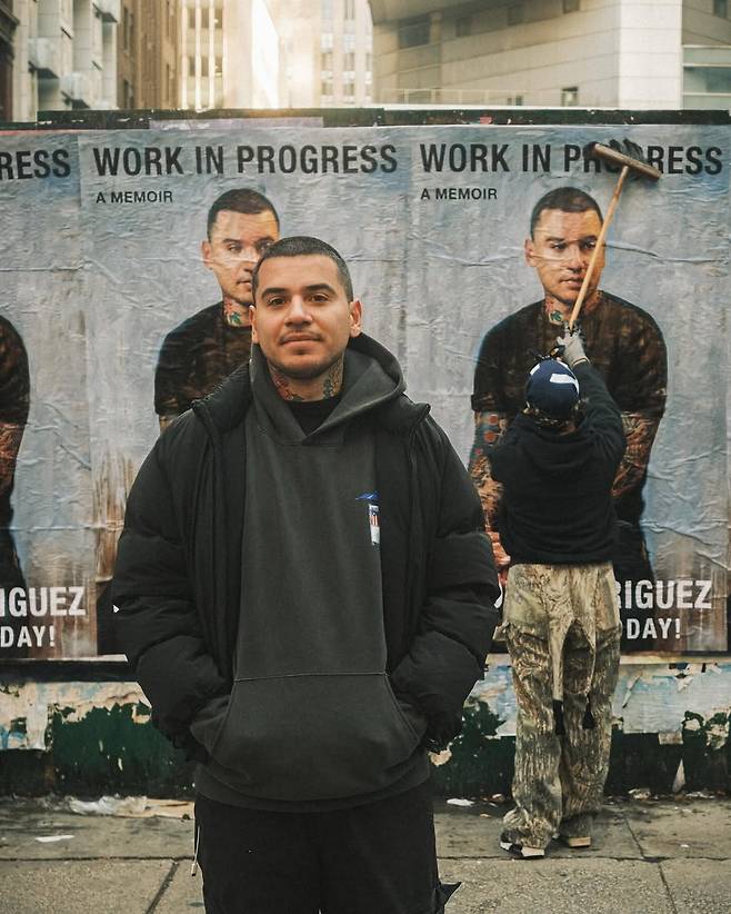 Rodriguez stands in front of posters for his memoir, "Work in Progress." (@devonrodriguezart, Instagram)