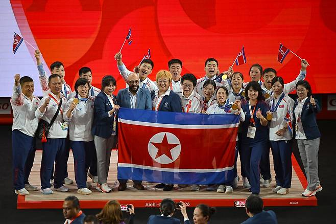 북한 역도 선수단이 28일 일본 나고야시 중소기업진흥회관에서 열린 2026 아이치·나고야 아시안게임 역도 남자 85㎏급 시상식이 끝난 뒤 금메달을 목에 건 로광렬과 함께 시상대에서 기념사진을 찍고 있다. 북한 역도는 이번 대회에 출전한 10명 전원이 메달을 따 금 7개, 은 2개, 동 1개를 기록했다. 나고야=하상윤 기자