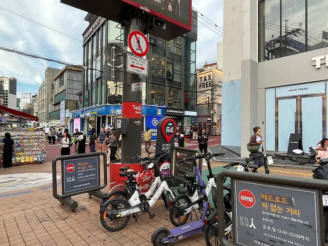지난 28일 '킥보드 없는 거리' 시범 운영 중인 홍대 레드로드의 킥보드 금지 표지 아래 공유 자전거와 킥보드가 주차되어 있다. /사진=전나경 기자