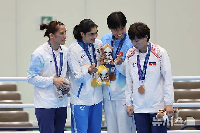 일본 아이치현 니시오시 니시오 체육관에서 열린 2026 아이치·나고야 아시안게임 복싱 여자 65kg 시상식에서 동메달을 획득한 북한 황효순(오른쪽)이 다른 메달 수상자들과의 손하트 기념촬영을 거부하고 자리를 이동하고 있다. /사진=뉴시스
