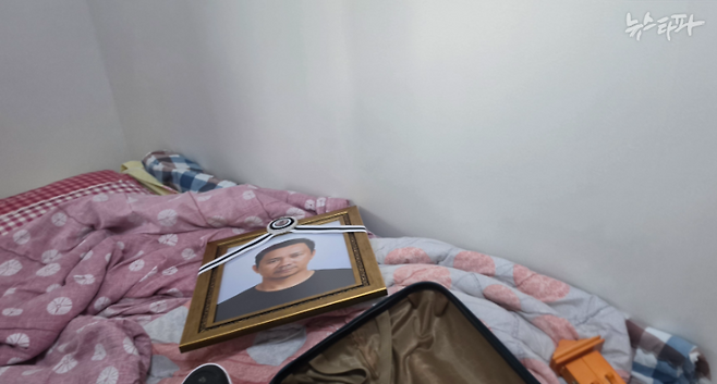 조이 칸토 씨가 숨지기 전까지 지낸 공장 부지 안 기숙사 방. 침구 위에 영정 사진이 놓여 있다.