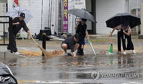 폭우 속 선행 (고양=연합뉴스) 배재만 기자 = 폭우가 쏟아진 18일 경기도 고양시 일산서구에서 시민들이 낙엽이 배수구를 막아 도로가 물바다가 되자 손으로 낙엽을 걷어내고 있다. 2026.10.18 scoop@yna.co.kr