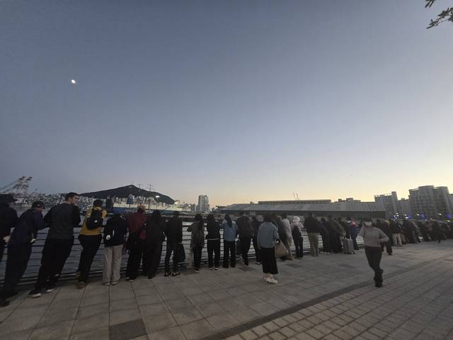 부캉이 3차 외해 유도 작업이 끝난 21일 오후 부산 북항친수공원 수변에서 시민들이 옛 부산항 1부두 쪽을 지켜보고 있다.