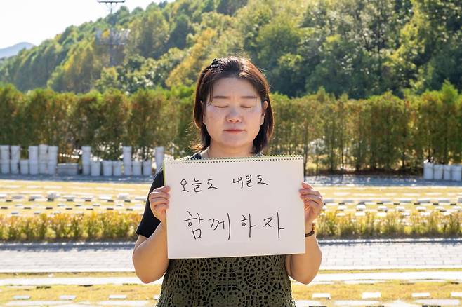 경기의 한 추모공원에서 23일 이태원 참사 유가족 김은미씨가 딸 오지민양의 묘소 앞에서 소망을 적어서 들고 있다. 최주연 기자