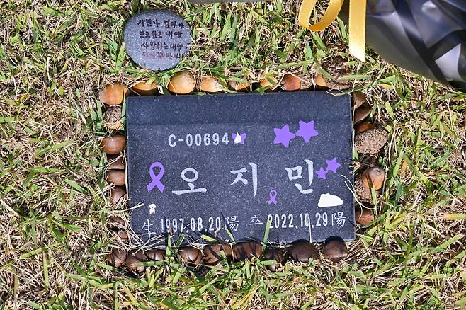 23일 경기의 한 추모공원에 위치한 오지민씨의 비석에 이태원 참사 애도를 뜻하는 보라색 리본 등과 김은미씨가 오대산에서 주워온 도토리들이 놓여 있다. 최주연 기자