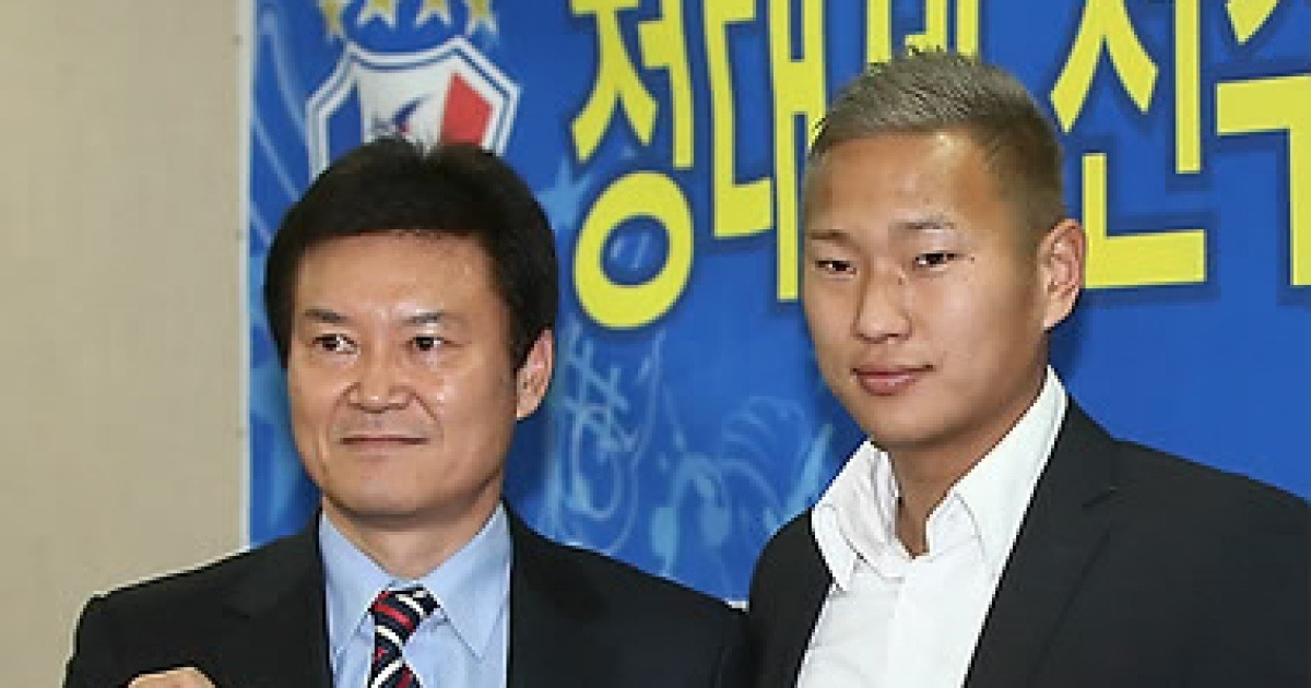 North Korean striker Jong Tae Se, right, holds his new jersey of South Korean  soccer club Suwon Bluewings with the team's Chief Executive Lee Seok-myung  during a press conference in Seoul, South