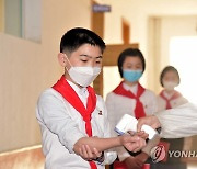복도에서 마스크 쓰고 체온 재는 북한 중학생들