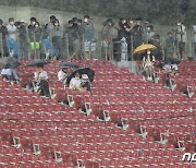 갑자기 내리는 비에 경기장 아래 몸 숨긴 관중들
