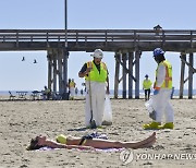 일광욕 여성 주변서 기름 찌꺼기 치우는 미 방재요원들