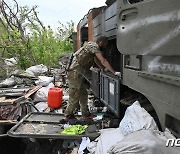 파괴된 러 군용 차량 살펴보는 우크라 병사
