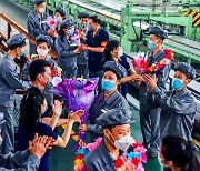 '수도 건설'에 이바지 해 축하를 받고 있는 북한 공장 노동자
