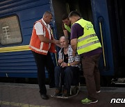 포크롭스크에서 온 기차 승객의 휠체어를 미는 자원봉사자