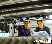생산 기계 살펴보는 북한 평양통신기계공장 노동자들