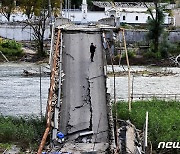 러군 폭격에 무너진 다리서 휴대전화 보는 남성