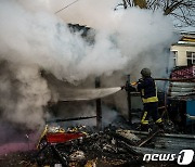 러시아 공격으로 화재 발생한 상점 진화하는 헤르손 소방관