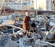 무너진 건물 잔해 위에서 망연자실한 표정