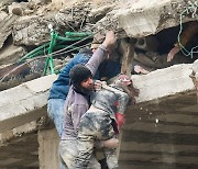 무너진 건물 잔해에서 구조되는 부상 소녀