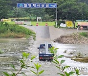 '아슬아슬' 잠긴 도로 건너는 화물차