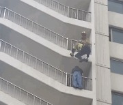 Firefighter saves woman hanging from high-rise balcony