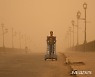 모래폭풍 속 카트 미는 이라크 남성