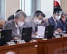 회의자료 살피는 국회 언론특위 민주당 의원들